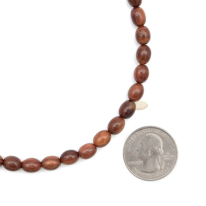Brown wooden Islamic misbaha prayer beads with elongated oval beads and green tassels.